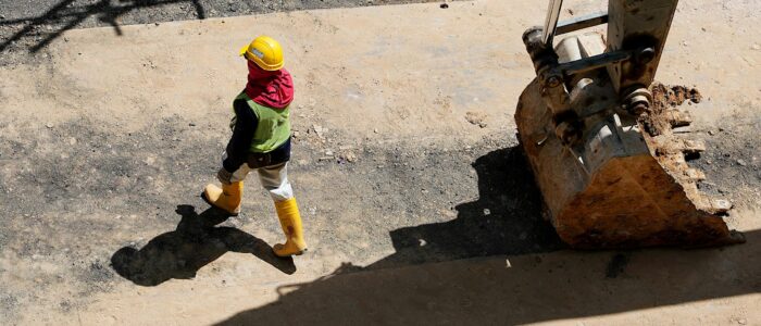 High Angle Photo of Person Walking Near Backhoe